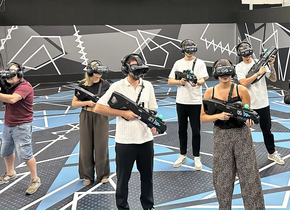 A group of players wearing headsets and carrying guns in the arena
